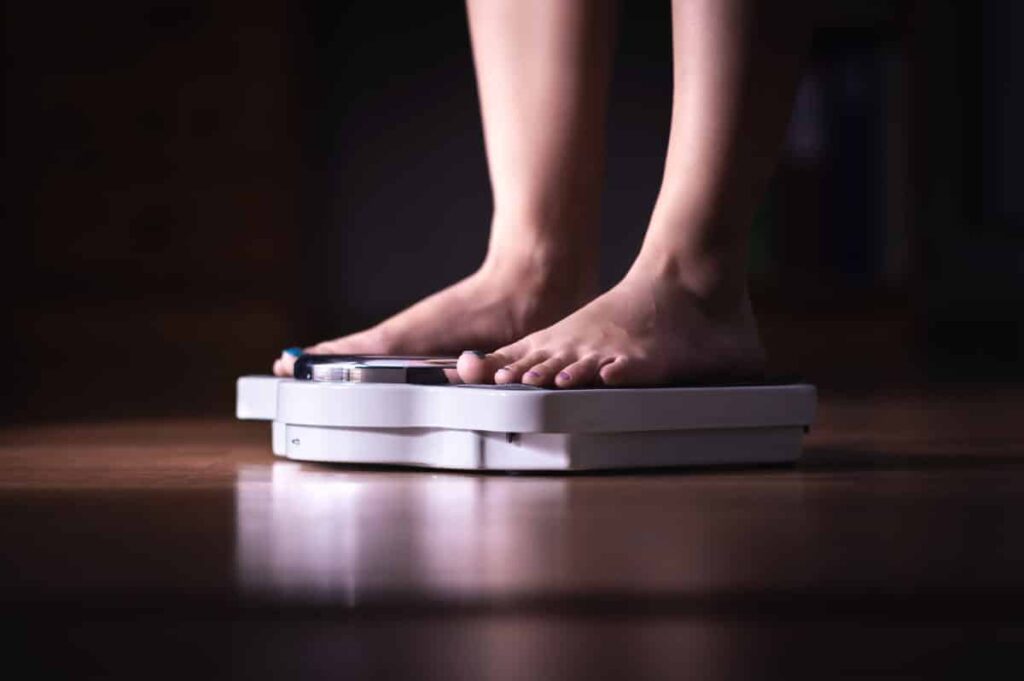 Feet on scale. Weight loss and diet concept. Woman weighing herself. Fitness lady dieting. Weightloss and dietetics. Dark late night mood.