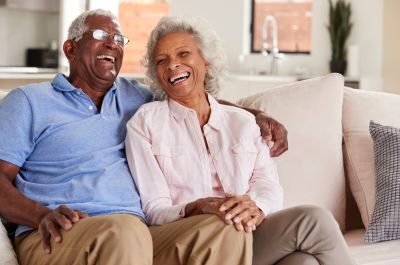 Alzheimer's disease study with a husband and wife couple smiling while sitting on a couch.